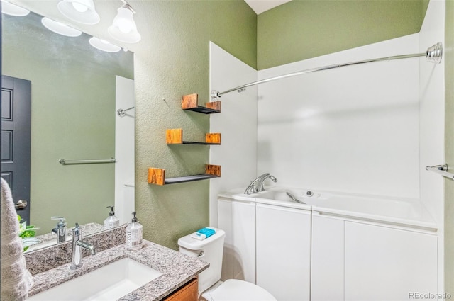 bathroom with toilet, a bath, and vanity