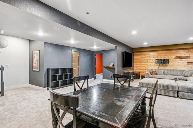 carpeted dining space featuring wooden walls