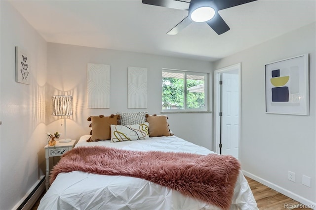 bedroom with light hardwood / wood-style flooring, a baseboard heating unit, and ceiling fan