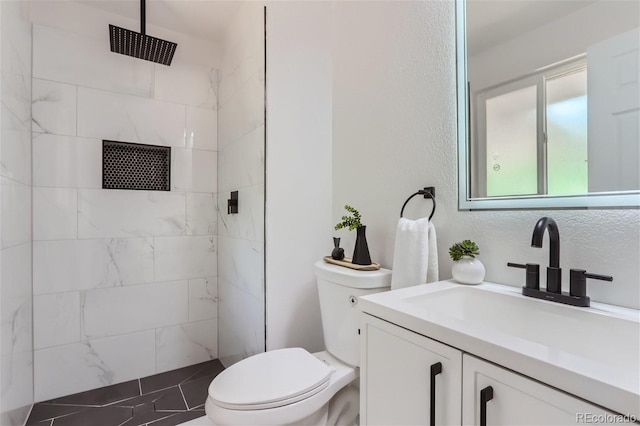 bathroom featuring vanity, toilet, and a tile shower