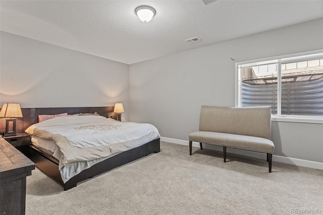 bedroom featuring a textured ceiling and light carpet