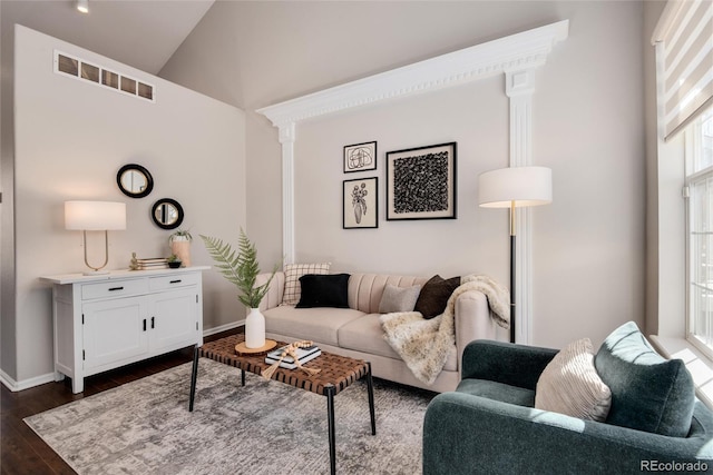 living room featuring high vaulted ceiling, decorative columns, and dark wood-type flooring