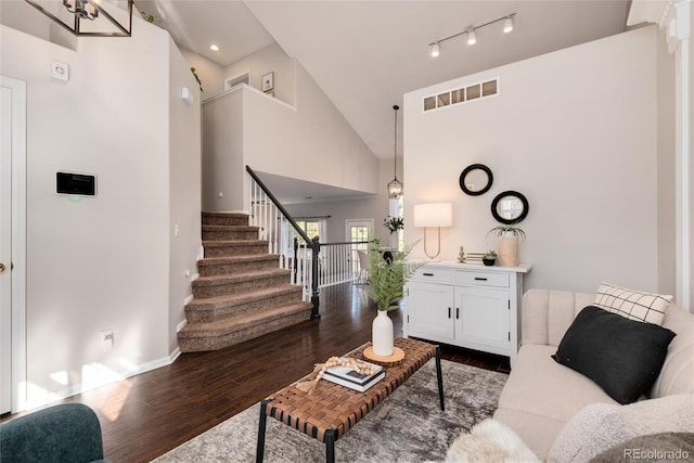 living room with a towering ceiling and dark hardwood / wood-style flooring