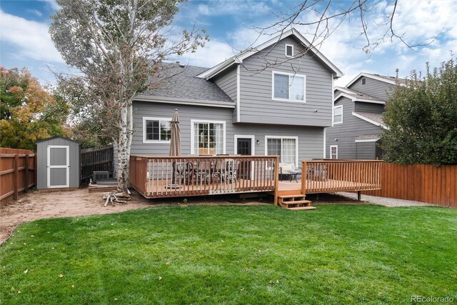 rear view of property with a deck, a yard, and a storage shed