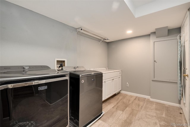 clothes washing area featuring washing machine and dryer and cabinets