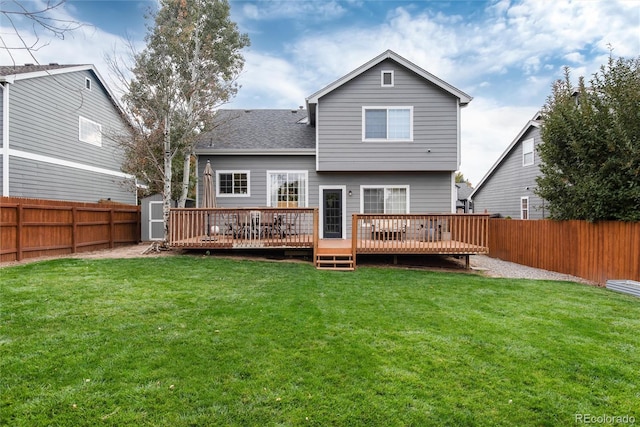 back of house featuring a deck, a storage unit, and a lawn