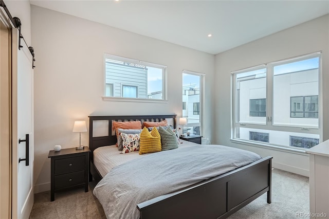 bedroom featuring a barn door and light colored carpet