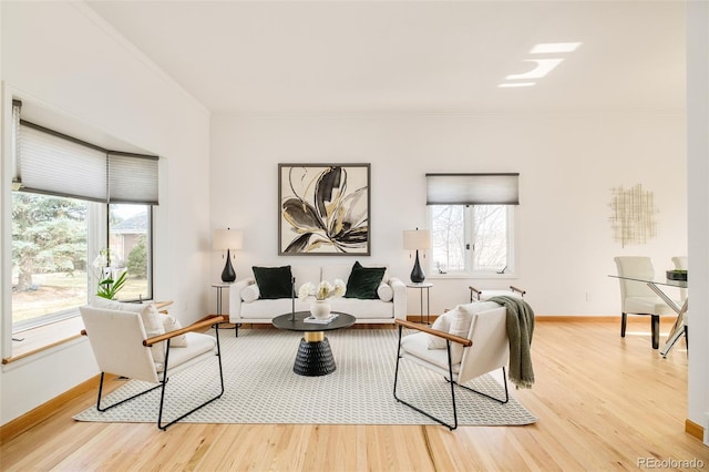 living room with a healthy amount of sunlight, light wood finished floors, baseboards, and ornamental molding