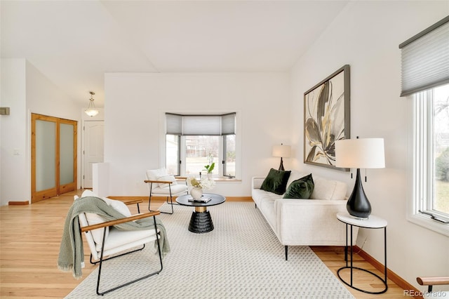 living room featuring baseboards, light wood-type flooring, and a healthy amount of sunlight