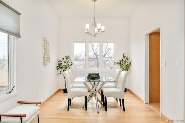 dining area featuring a chandelier, baseboards, crown molding, and light wood finished floors