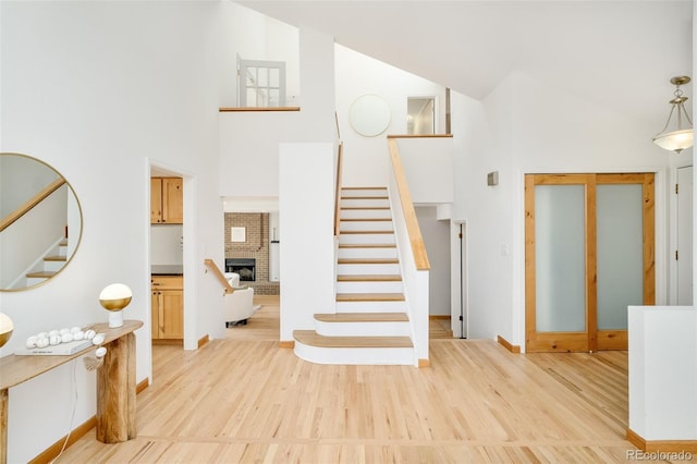 stairway featuring high vaulted ceiling, a fireplace, and wood finished floors