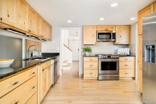 kitchen featuring light wood-style floors, appliances with stainless steel finishes, a sink, and light brown cabinetry