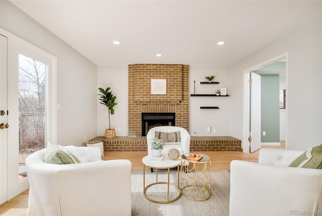 living room featuring light wood-type flooring, a brick fireplace, and recessed lighting