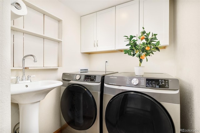 clothes washing area featuring washing machine and clothes dryer and cabinet space