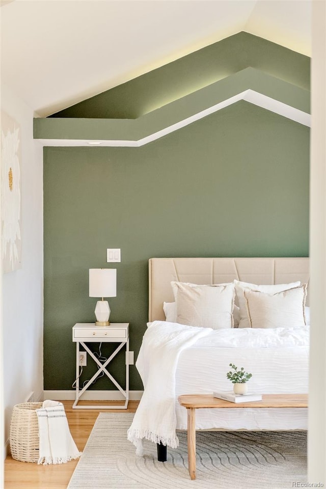 bedroom with lofted ceiling and wood finished floors