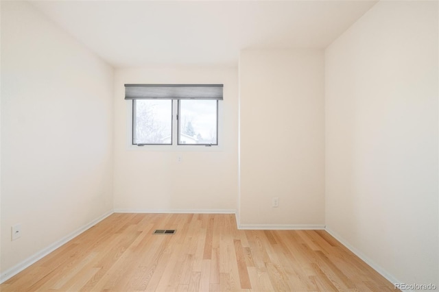 spare room with visible vents, light wood-style flooring, and baseboards