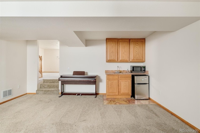 kitchen with light colored carpet, visible vents, appliances with stainless steel finishes, a sink, and baseboards