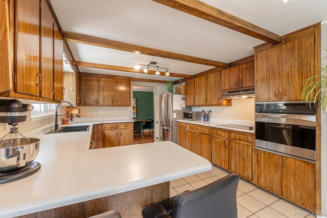1521 Columbine Blvd, Colorado Springs, CO 80907 - kitchen with appliances with stainless steel finishes, under cabinet range hood, beam ceiling, light countertops, and a peninsula