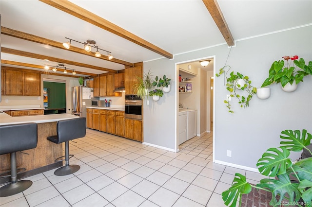 1521 Columbine Blvd, Colorado Springs, CO 80907 - kitchen with appliances with stainless steel finishes, beamed ceiling, separate washer and dryer, brown cabinetry, and light countertops