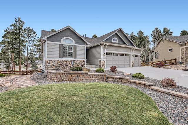 craftsman inspired home with a front lawn, driveway, stone siding, fence, and an attached garage