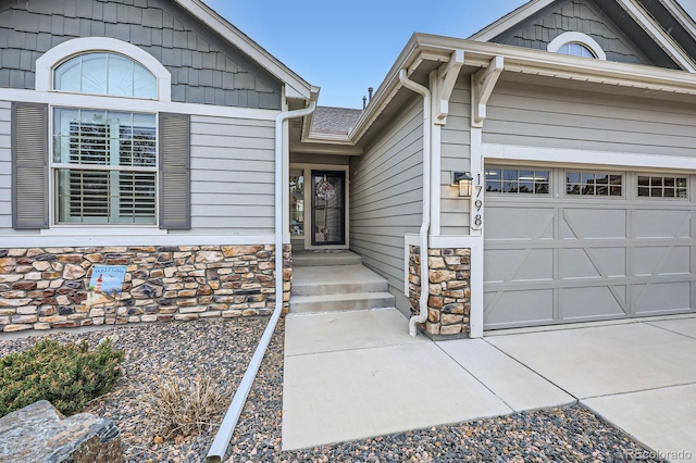 entrance to property featuring an attached garage and stone siding