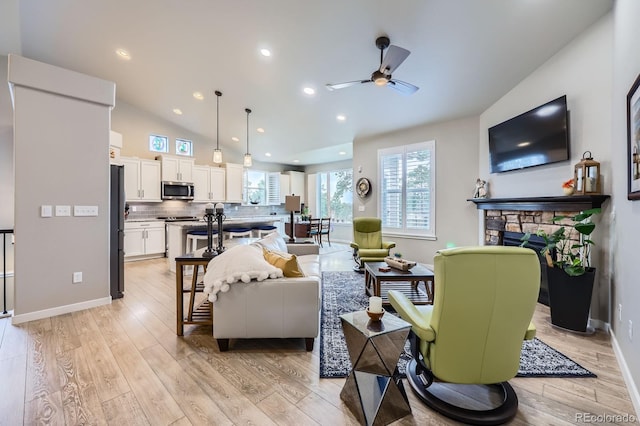 living room with ceiling fan, light wood finished floors, a fireplace, lofted ceiling, and recessed lighting