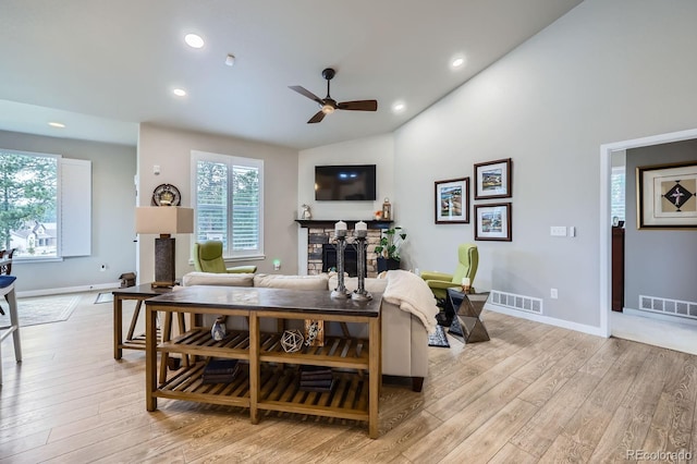 living area with a ceiling fan, visible vents, a fireplace, and light wood-style floors