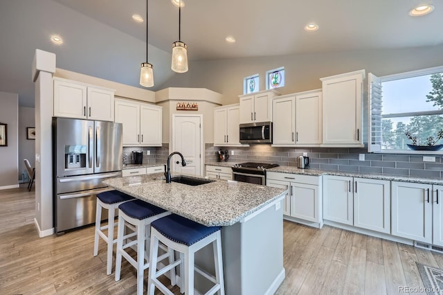 kitchen featuring a sink, decorative backsplash, a healthy amount of sunlight, stainless steel appliances, and lofted ceiling