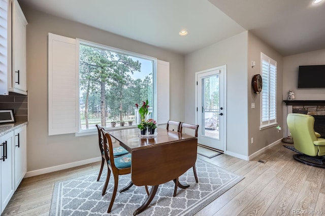 dining room with recessed lighting, light wood-style floors, a fireplace, and baseboards