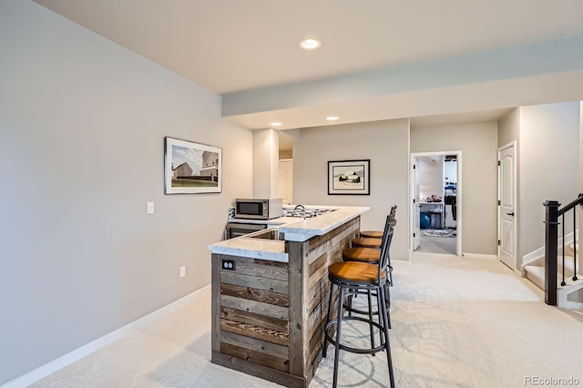 bar featuring light colored carpet, stainless steel microwave, baseboards, and stairs