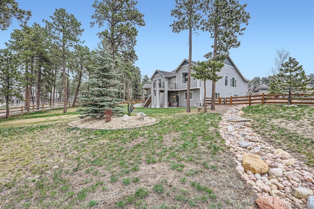view of yard with a wooden deck, stairs, and fence