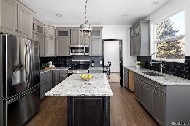 kitchen featuring a kitchen island, appliances with stainless steel finishes, decorative light fixtures, sink, and gray cabinetry