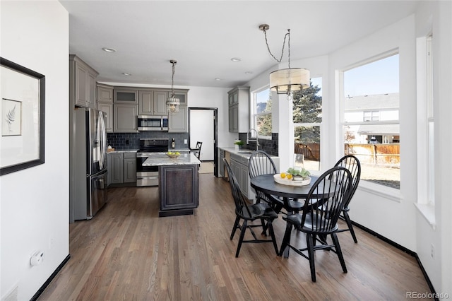 kitchen with a kitchen island, appliances with stainless steel finishes, gray cabinets, and hanging light fixtures