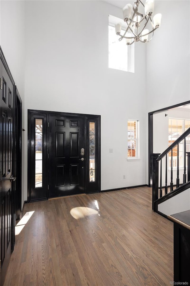 foyer with hardwood / wood-style flooring, a chandelier, and a high ceiling