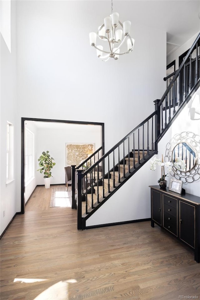 staircase featuring hardwood / wood-style flooring, a chandelier, and a high ceiling