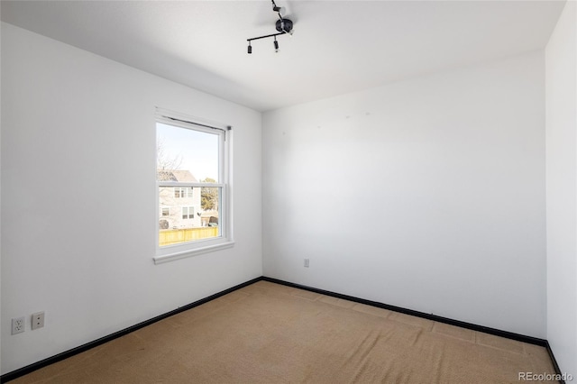 empty room featuring light colored carpet and track lighting