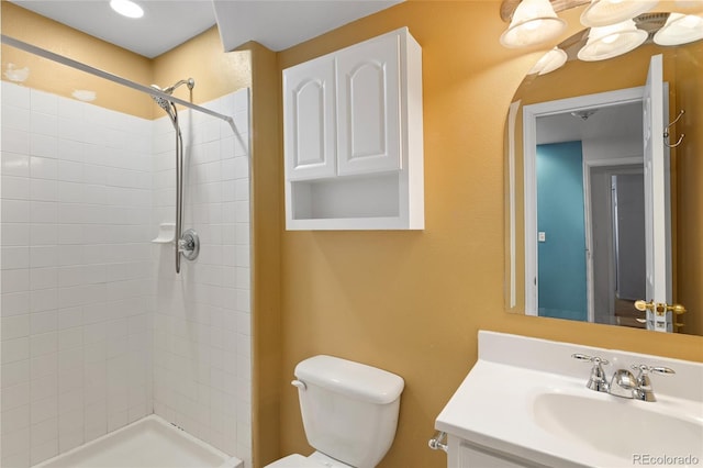 bathroom with tiled shower, vanity, and toilet