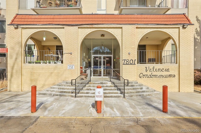 view of exterior entry with a tile roof and brick siding