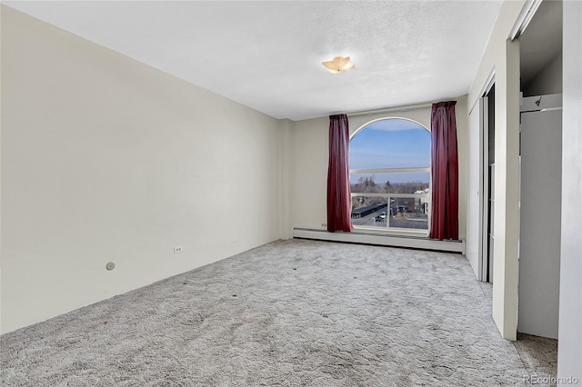 spare room featuring light carpet, a textured ceiling, and a baseboard radiator