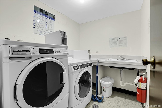 clothes washing area with washer and clothes dryer and a sink