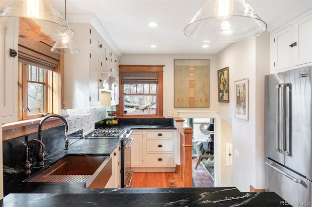 kitchen with a sink, decorative backsplash, stainless steel appliances, white cabinets, and dark countertops