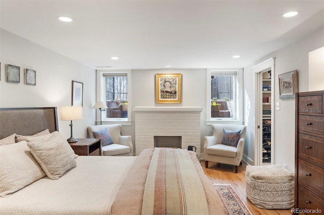 bedroom featuring visible vents, recessed lighting, a fireplace, and wood finished floors