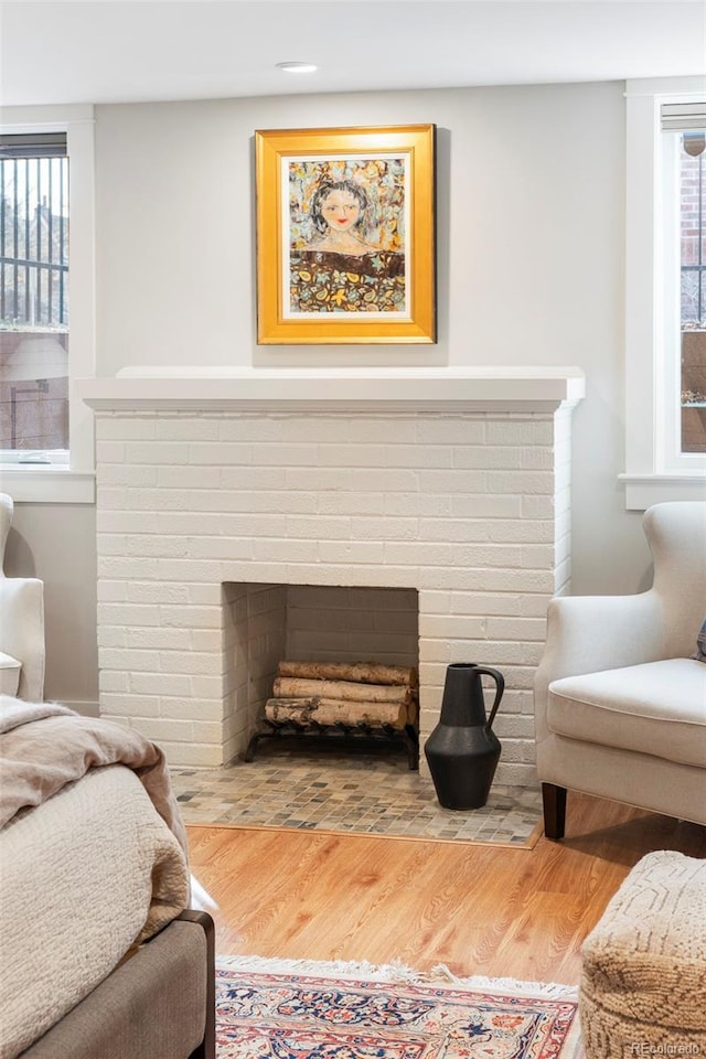 living room with a brick fireplace and wood finished floors