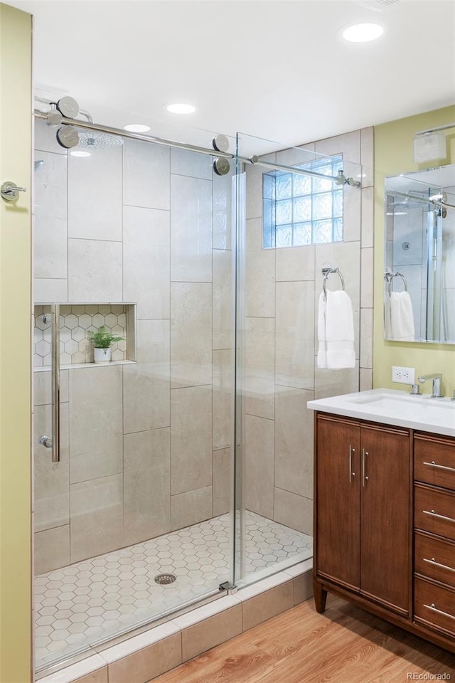 bathroom with wood finished floors, a stall shower, and vanity