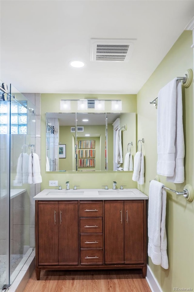 bathroom with visible vents, a shower stall, wood finished floors, and a sink