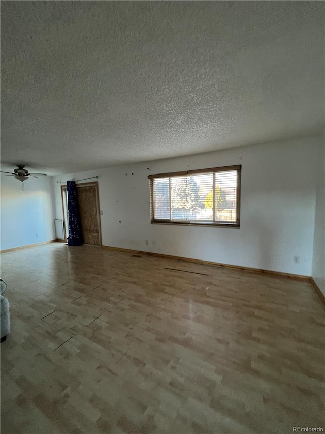 empty room with ceiling fan and a textured ceiling