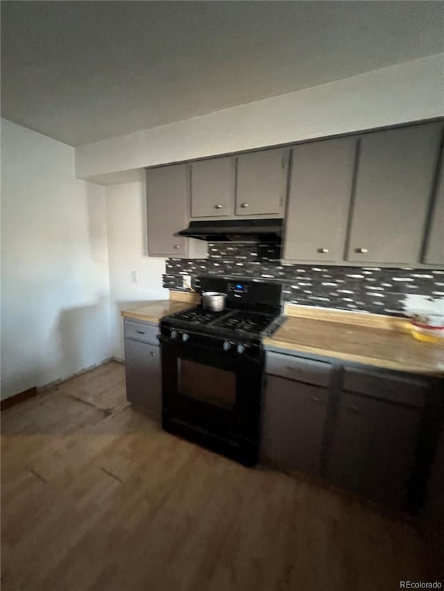 kitchen with black gas range oven, backsplash, dark hardwood / wood-style floors, and gray cabinetry