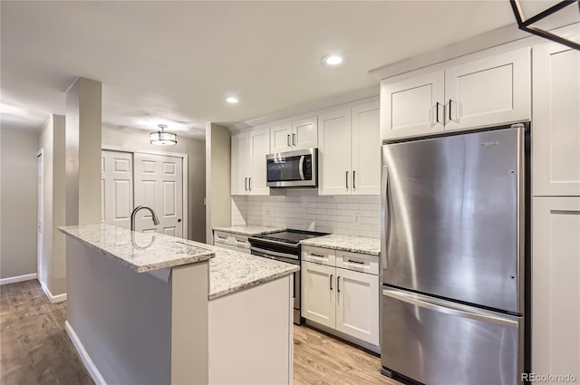 kitchen with appliances with stainless steel finishes, light wood-type flooring, white cabinetry, decorative backsplash, and recessed lighting