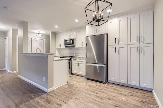 kitchen featuring stainless steel appliances, baseboards, a chandelier, recessed lighting, and backsplash