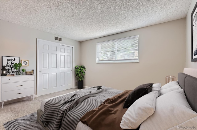 bedroom featuring light colored carpet, a textured ceiling, and a closet
